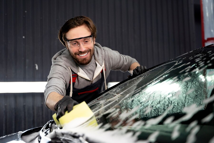 man cleaning the car's windshield using a sponge